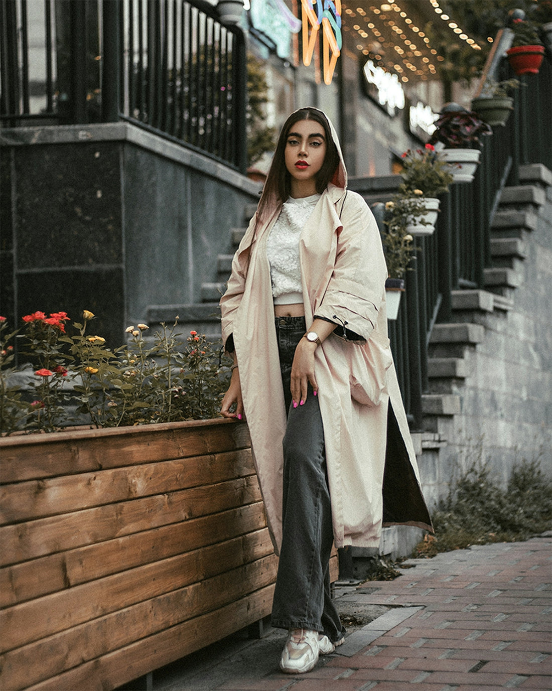 a woman standing on a sidewalk next to a planter