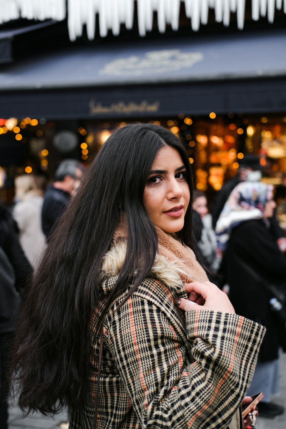a woman with long black hair standing in front of a store