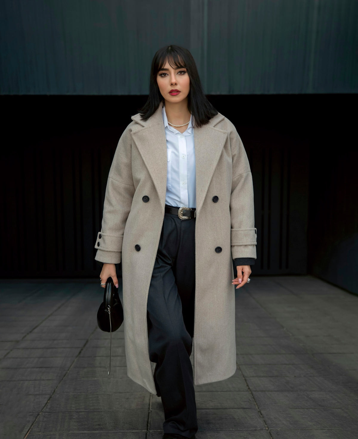 Stylish woman in a coat walks towards the camera.