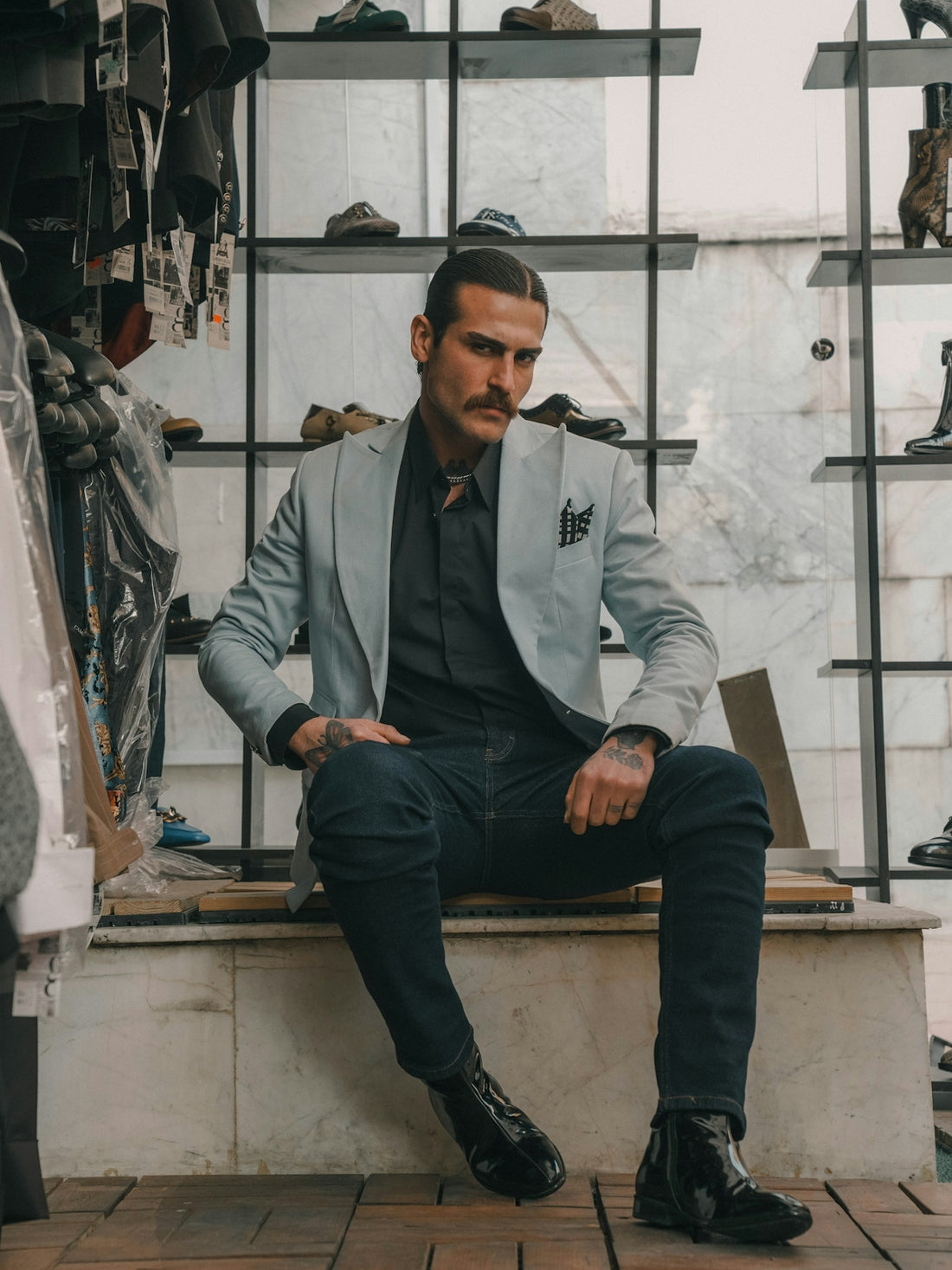 A well-dressed man sits in a shoe store.